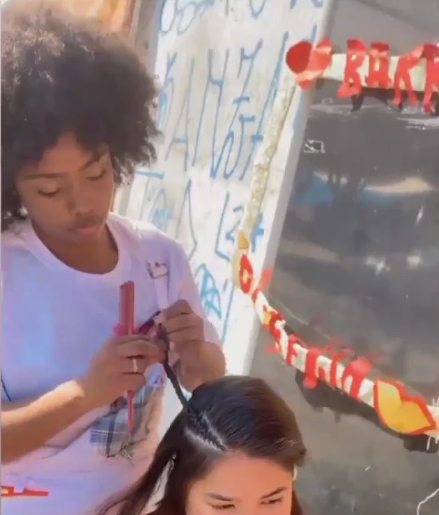 Renata trançando o cabelo de uma cliente na rua, no começo do trabalho